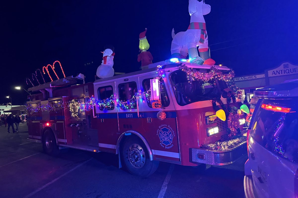 A fire engine strung with lights, carrying lit inflatable figures